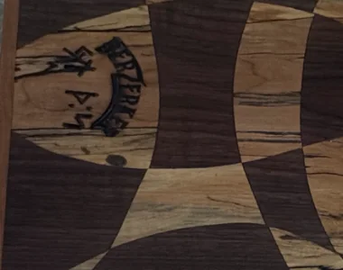 Close view of the large cutting board's interlocking light-and-dark geometric pattern and inset maker's mark.